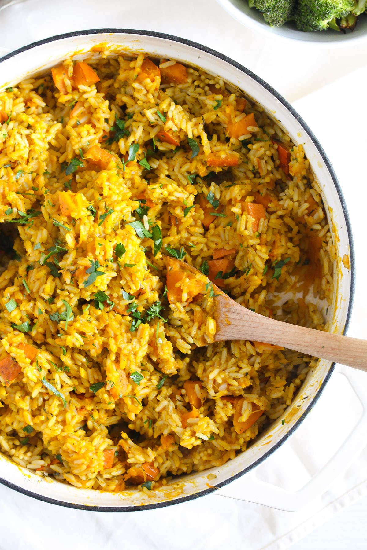 stirring pumpkin rice with a spoon in a large dutch oven.