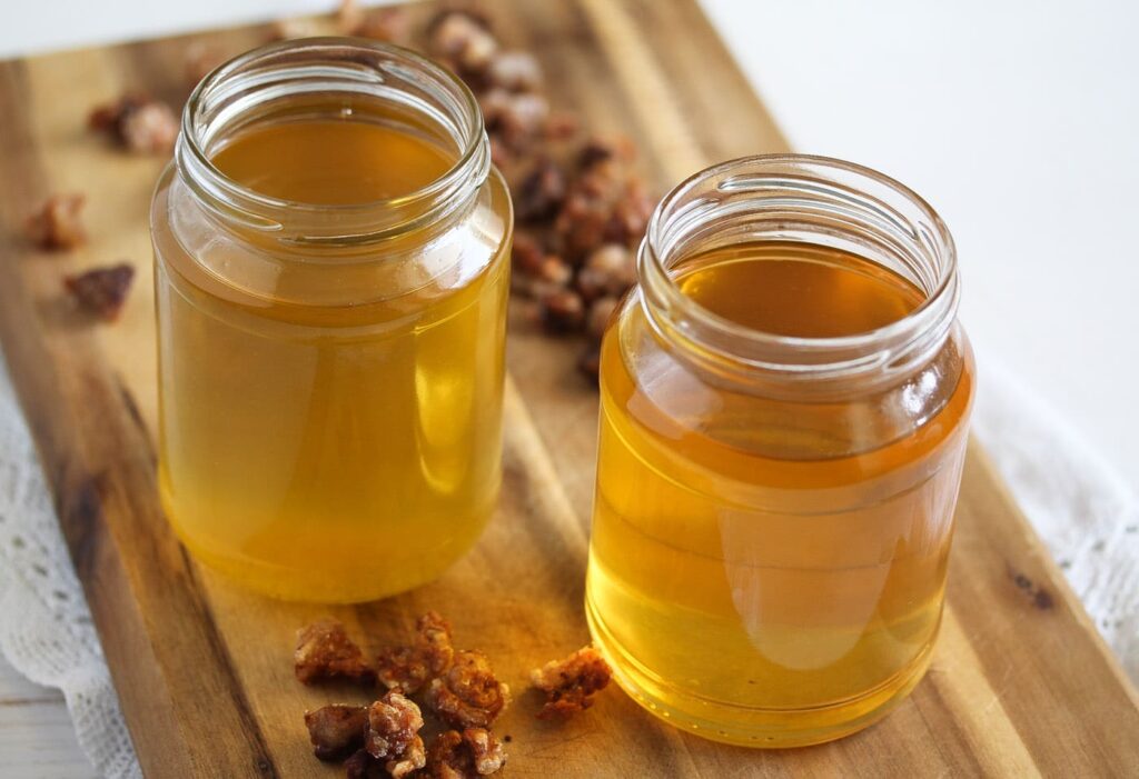 rendered fat in jars and cracklings on a wooden board