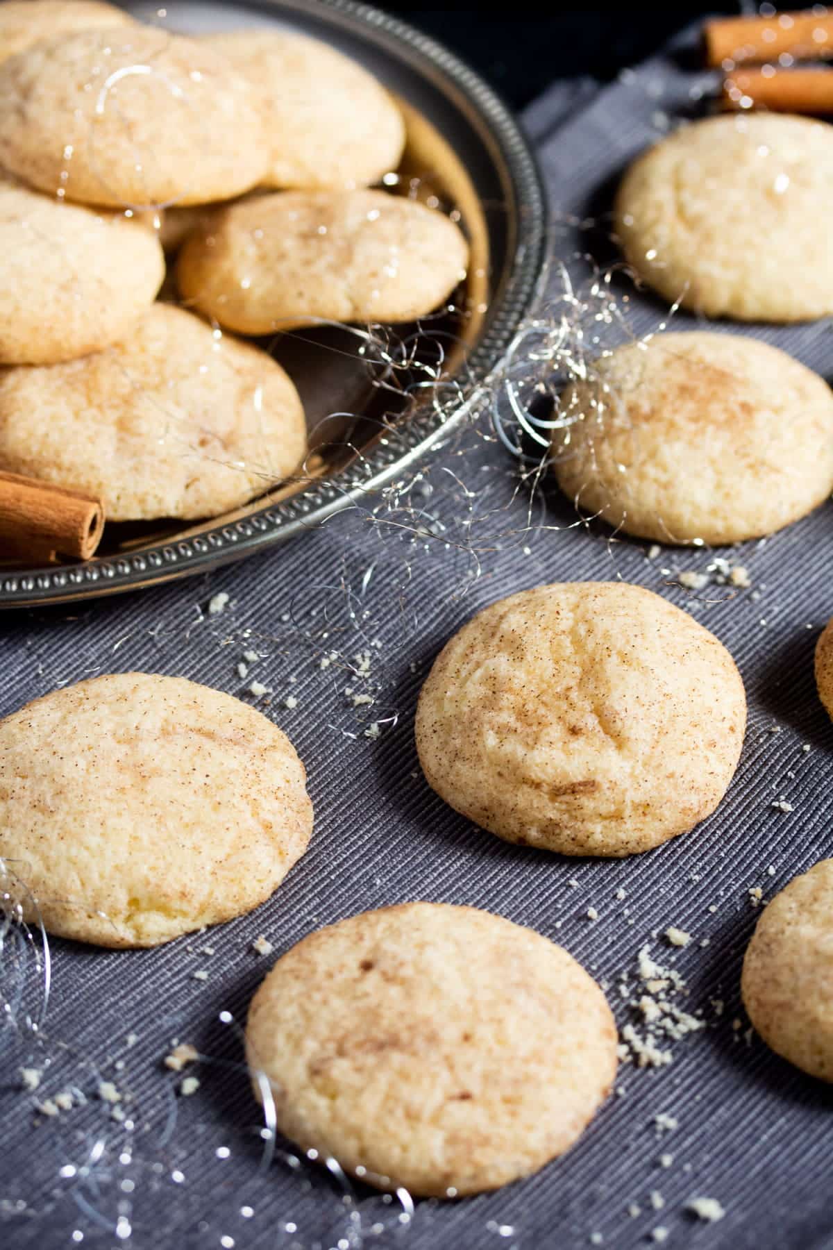 snickerdoodles on a silver platter and on a black cloth.
