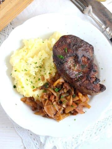 turkey liver with apple onions sauce and mashed potatoes on a large plate