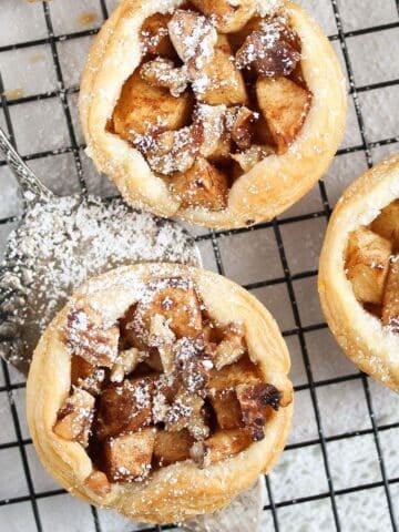 three puff pastry apple pies on a wire rack