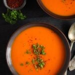 butternut soup with peppers on a dark table cloth