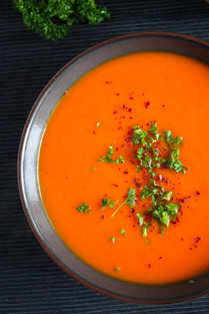 red pepper soup with squash in a dark bowl
