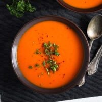 butternut squash and red pepper soup in a dark bowl.