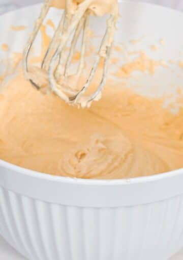 mixing buttercream with custard powder in a white bowl.