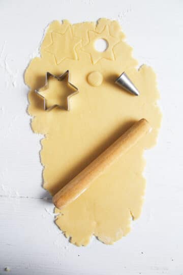 rolled cookie dough, a star cutter, a nozzle and a small rolling pin.