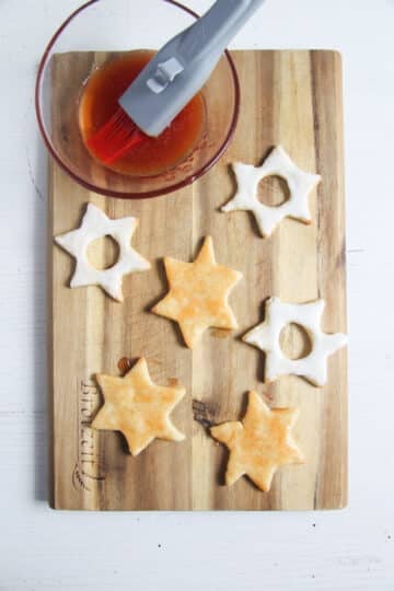 glazing baked star cookies with jam using a pastry brush.