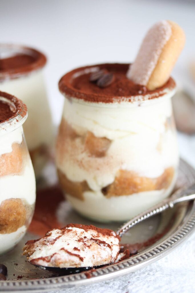 tiramisu cups on a platter and a spoonful of dessert