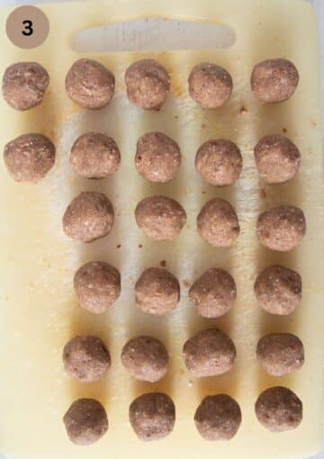 many unbaked polvorones cookies rolled into balls on a cutting board.