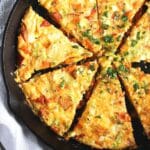 cast iron baked egg dish with cheese and vegetables