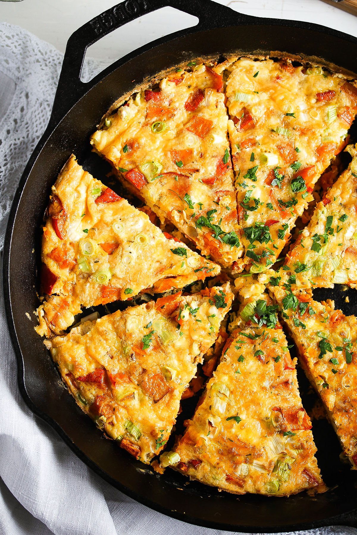 pumpkin frittata cut into wedges in a large cast iron skillet.