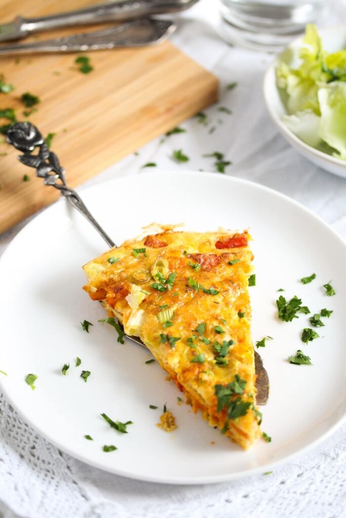 a slice of frittata with pumkin, feta and cheddar cheese on a plate