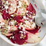 raw beetroot feta and apple salad on a platter with serving cutlery.
