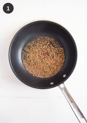 lots of spices roasted in a small frying pan. 