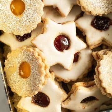 german spitzbuben cookies shaped like stards and round, filled with two types of jam and iced with sugar.