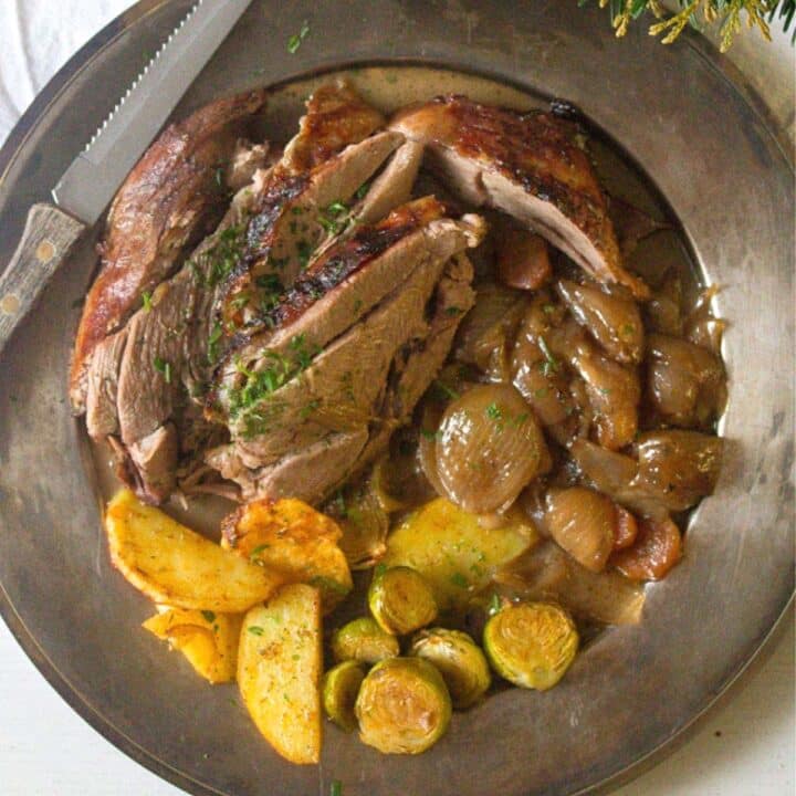 vintage plate with slices of roasted turkey leg, roast potatoes and shallots.