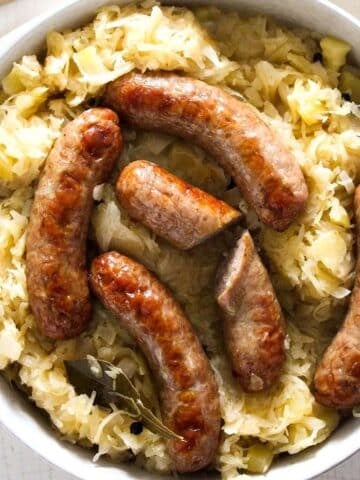 brats cooked in the oven in a bowl with sauerkraut.