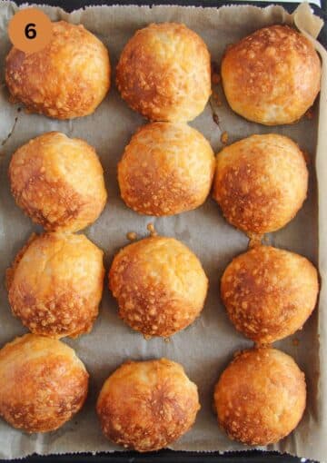 twelfe golden baked cheese buns on a baking tray.