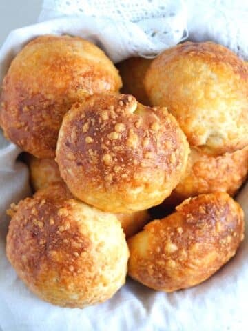 cheese buns in a basket lined with white kitchen cloth