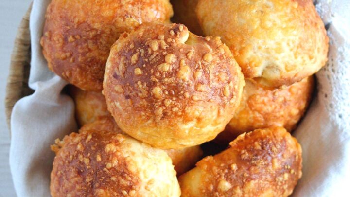 cheese buns in a basket lined with white kitchen cloth