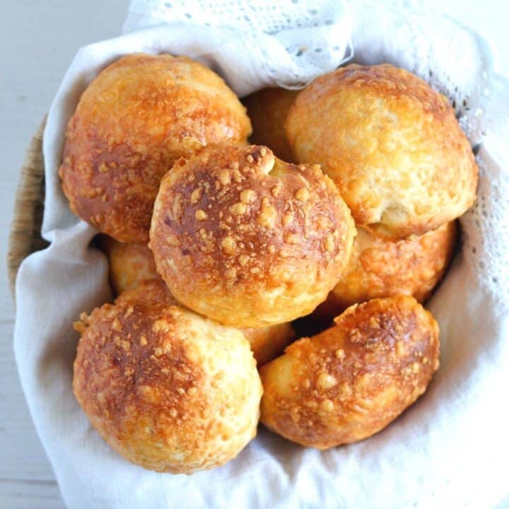 cheese buns in a basket lined with white kitchen cloth