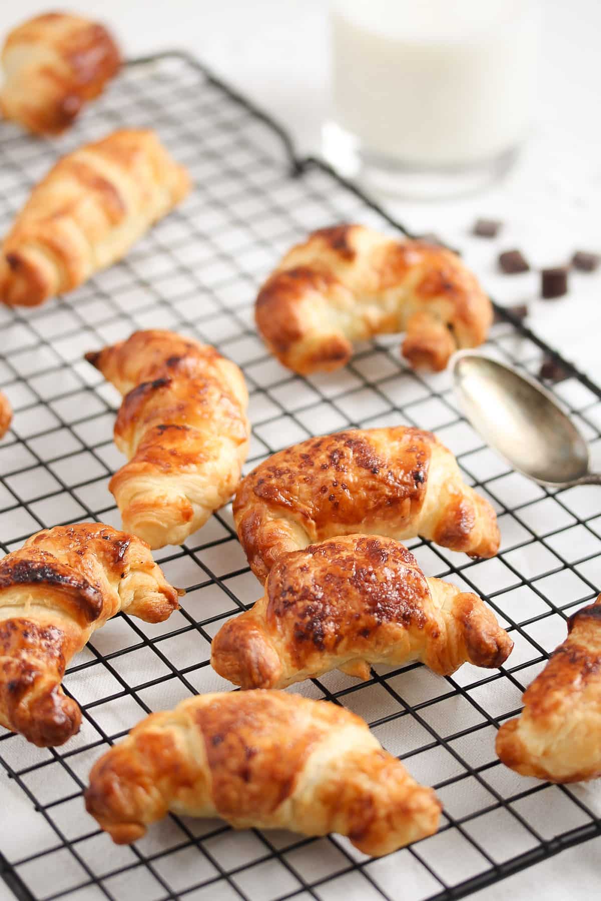 many small chocolate filled puff pastry pieces on a wire rack and a spoon.
