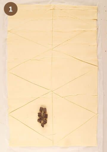 puff pastry sheet cut into squares, one of them with chocolate chunks on top.