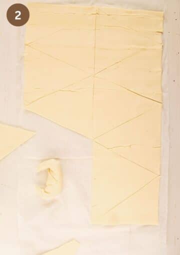 sheet of puff pastry cut into triangles and one shaped mini croissant.