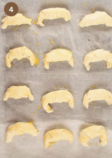 unbaked pastries with chocolate filling and brushed with egg on a baking sheet.