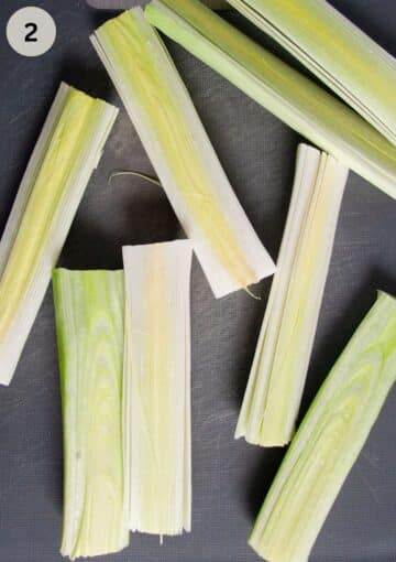 pieces of leek sliced lengthwise on a cutting board.