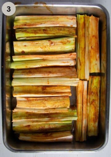 seasoned leek pieces in a roasting tin before baking.