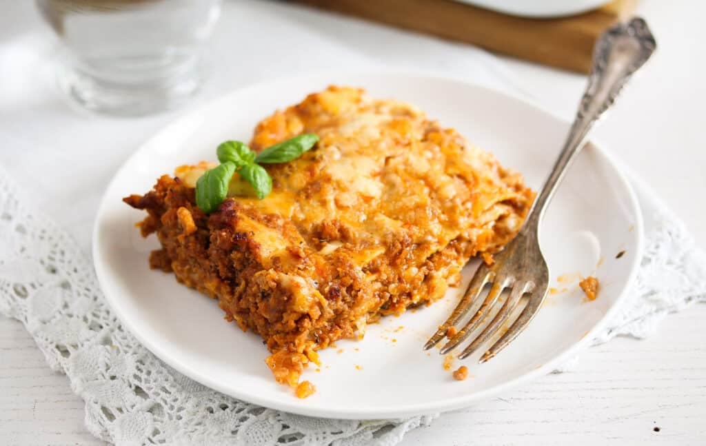 slice of pasta dish with meat sauce and bechamel on a white plate