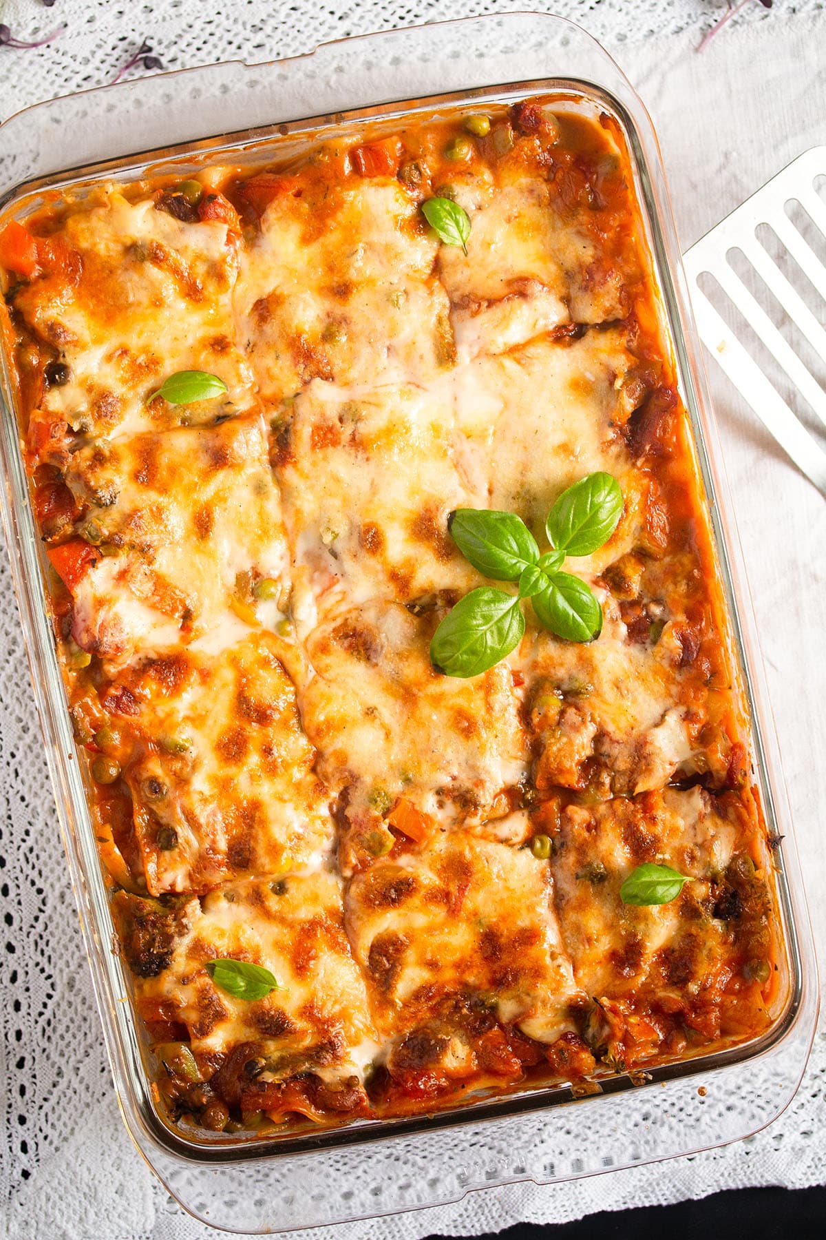 vegetable lasagna with white sauce in a baking dish.