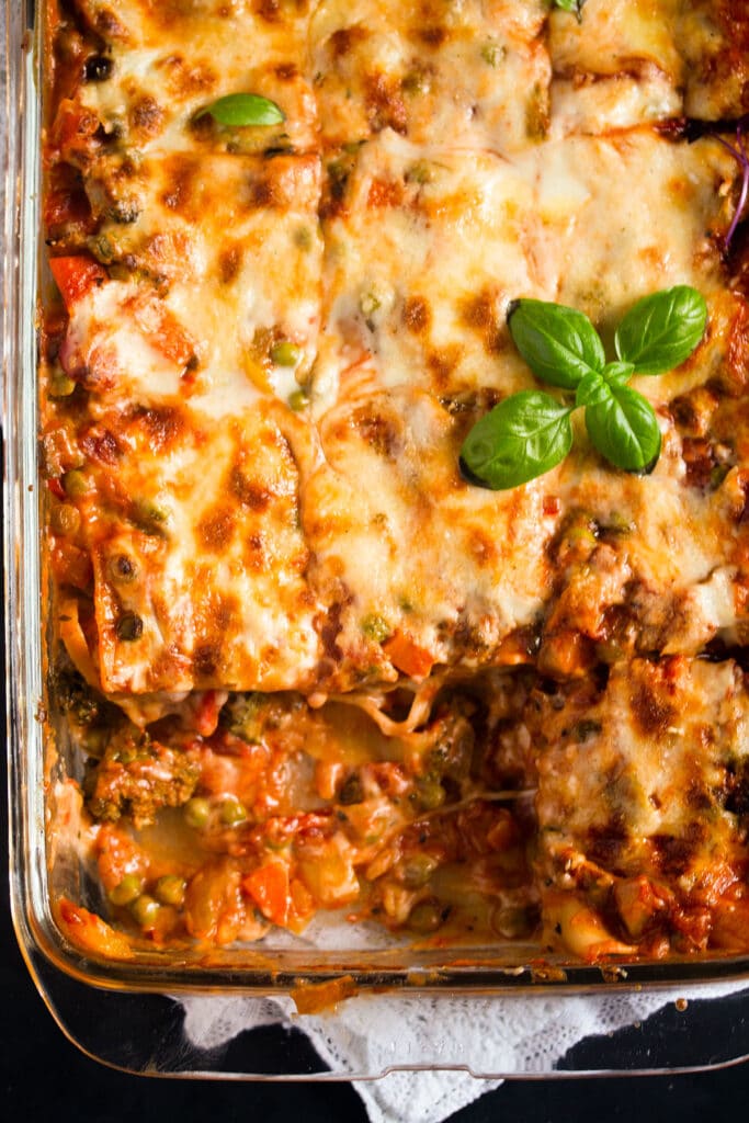 vegetarian lasagna with bechamel sauce with scooped pieces in a baking dish.