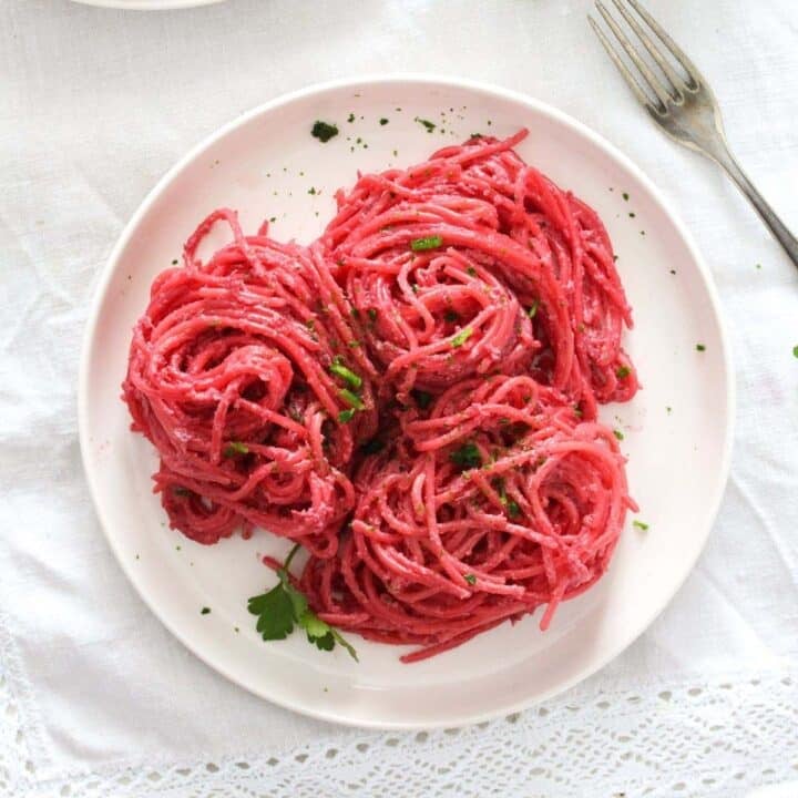 beetroot pasta on a small white plate sprinkled with parsley