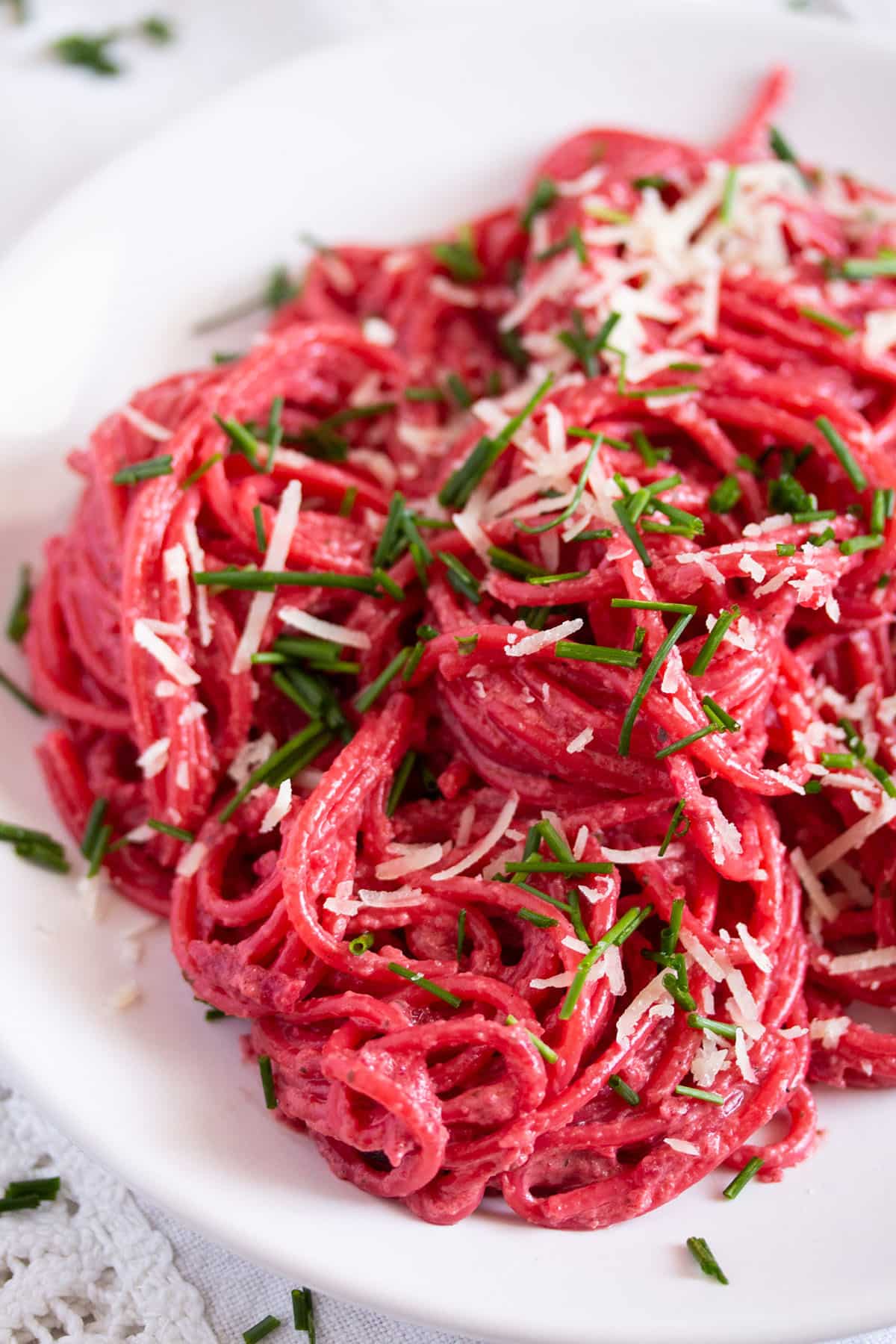 shiny beet pasta on a plate sprinkled with parmesan and herbs. 
