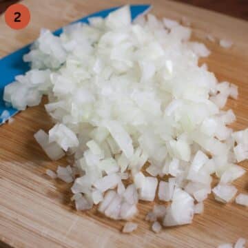 chopped onions and a knife on a wooden board.