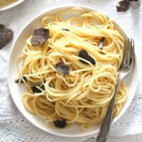 truffle pasta served on a small white plate with shavings on top.