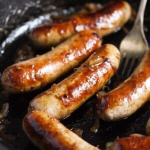 juicy, golden brown brats cooked on the stove in a skillet.