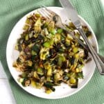 buttered leeks served on a small white plate with fork and knife.