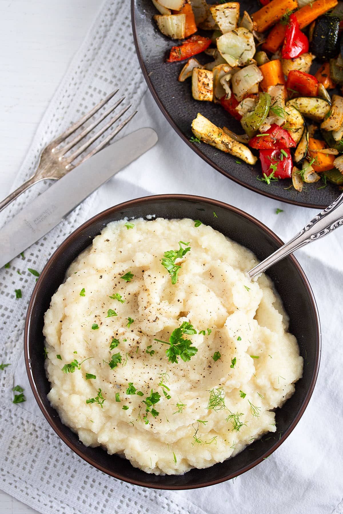 a bowl full of celery root mash and a plate of roasted vegetables.