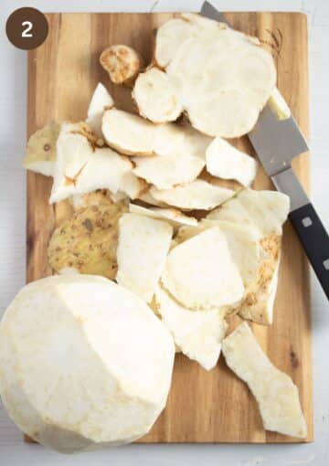 peeling a celeriac on a wooden board.