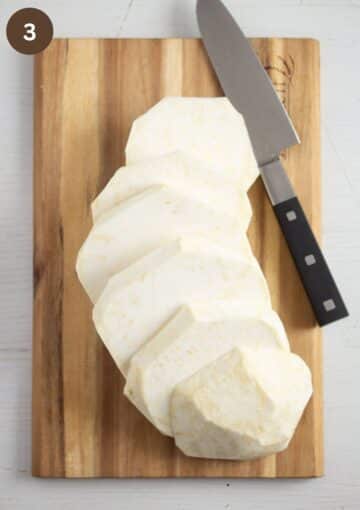 sliced celeriac and a knife on a wooden cutting board.