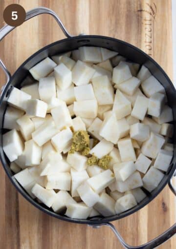 uncooked celeriac pieces and bouillon powder in a cooking pot.