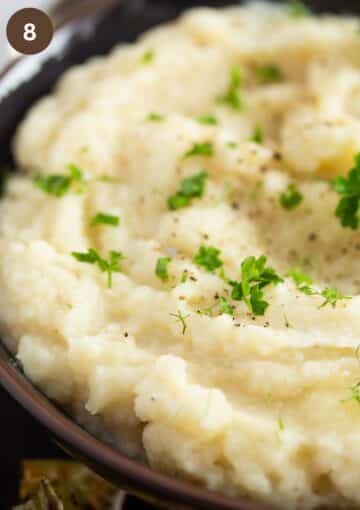 creamy mashed celery root sprinkled with parsley in a bowl.