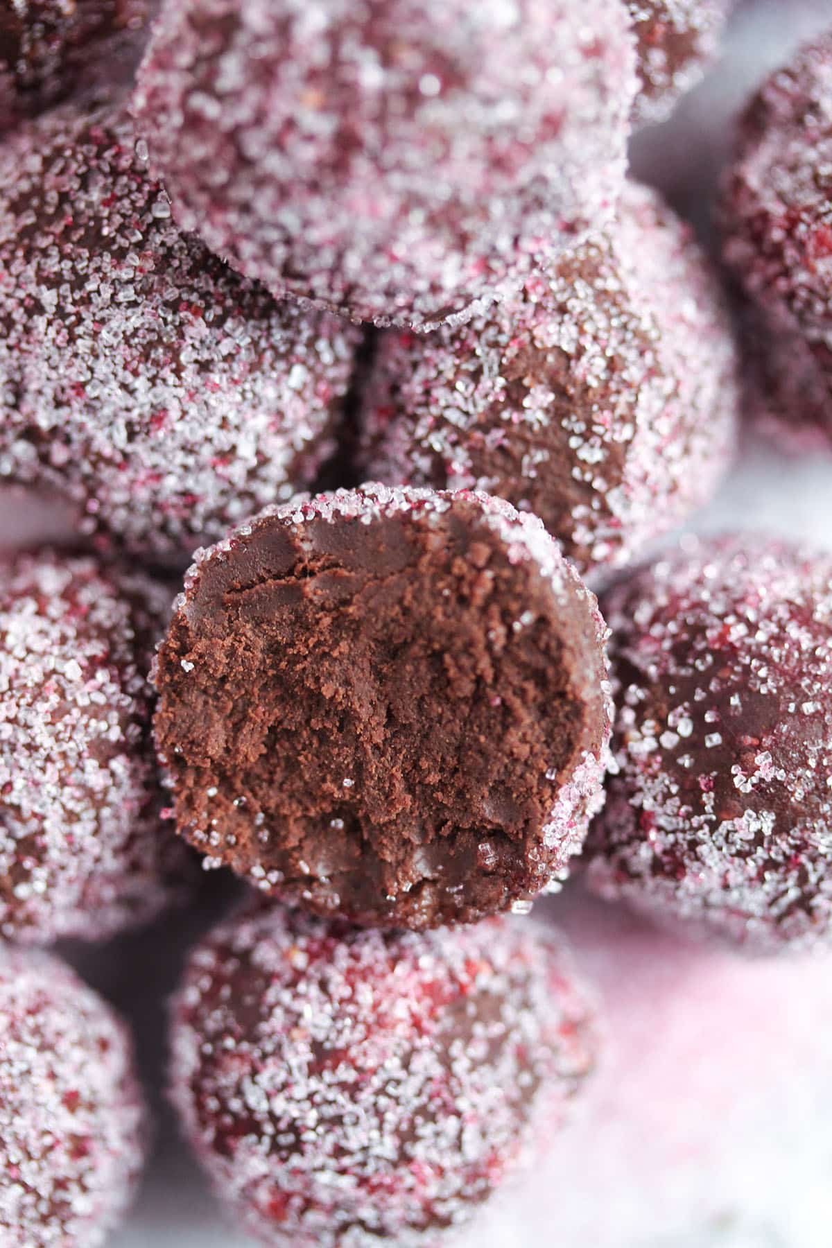 homemade champagne truffles, one bitten into to show the chocolate interior.