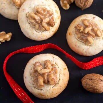 chinese walnut cookies on a black board and a red ribbon between them.