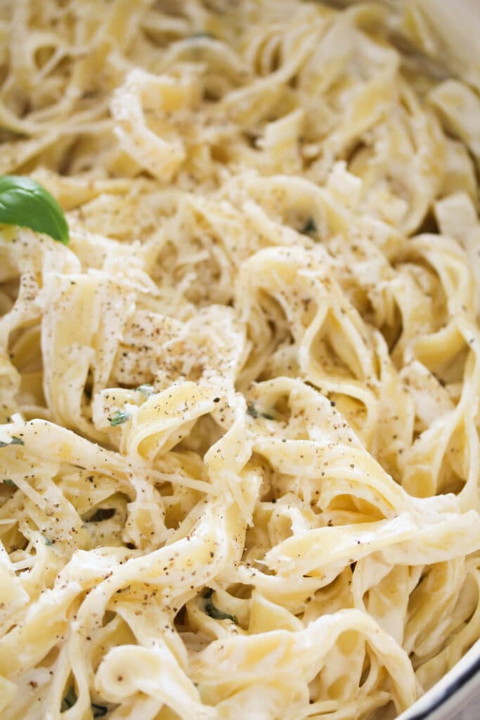close up creamy tagliatelle with cheese and basil sauce.