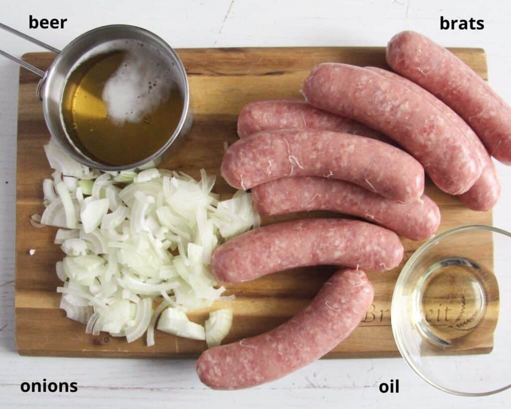 raw sausages, sliced onion, beer and oil on a wooden board