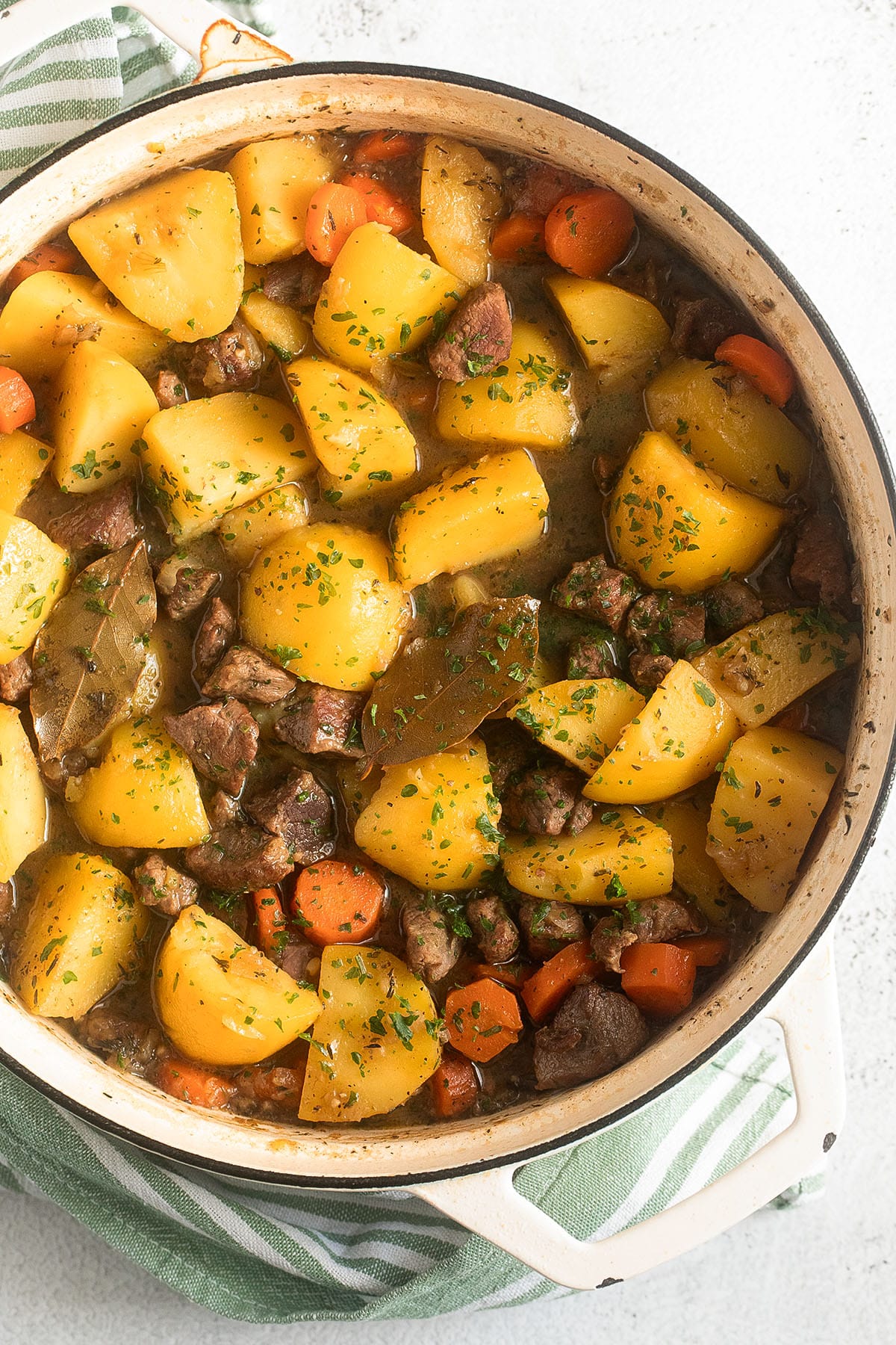 stew with lamb, potatoes and carrots in a large white pot.